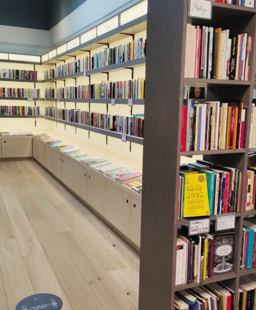 Modern white backlit shelves covered with books line the walls.