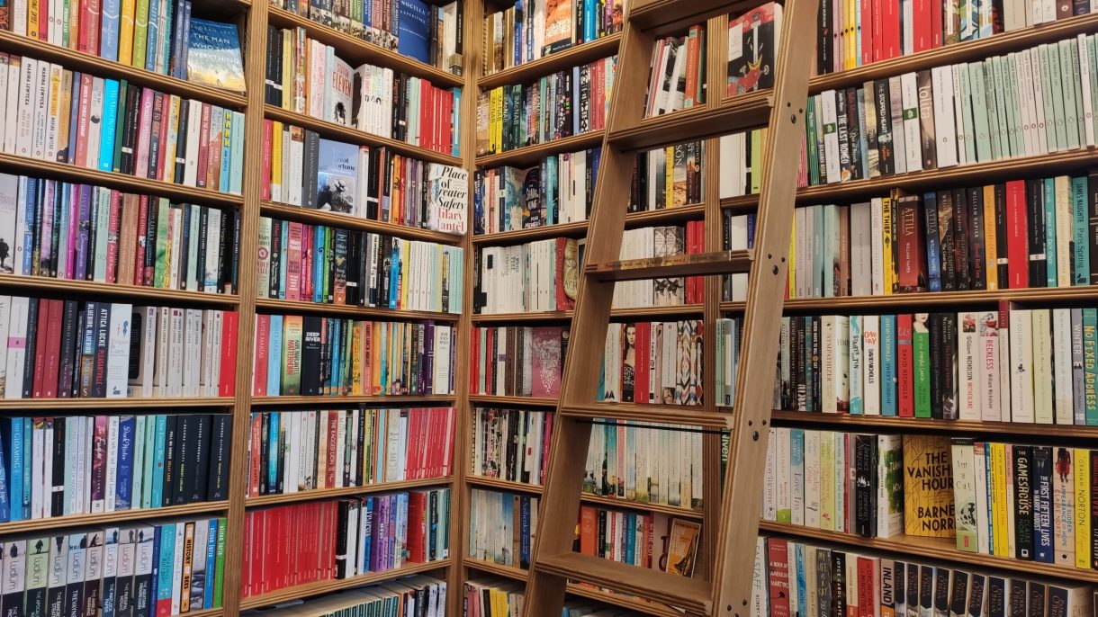 A brown ladder leans against colourful bookshelves at Toppings Bookshop