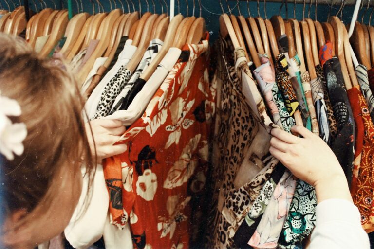 a girl rummages through colourful floral vintage dresses