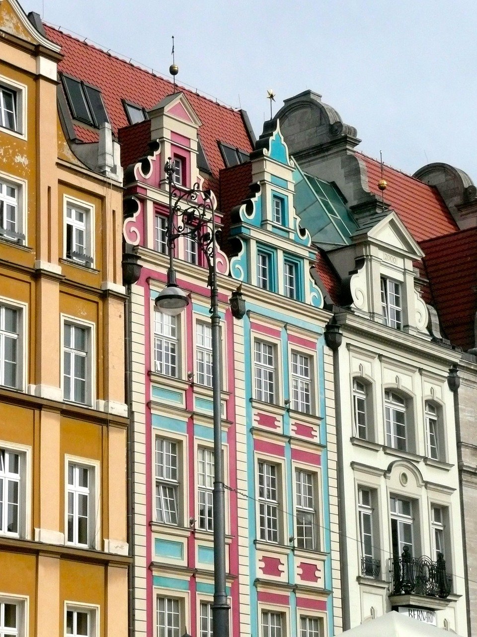 Colourful Polish Houses in yellow, pink and teal line a cobbled street.