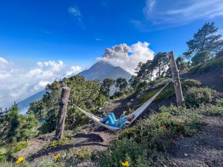 Alice lies in a hammock. Volcan Fuego is erupting in the background on the Acatenango Volcano Hike in Guatemala